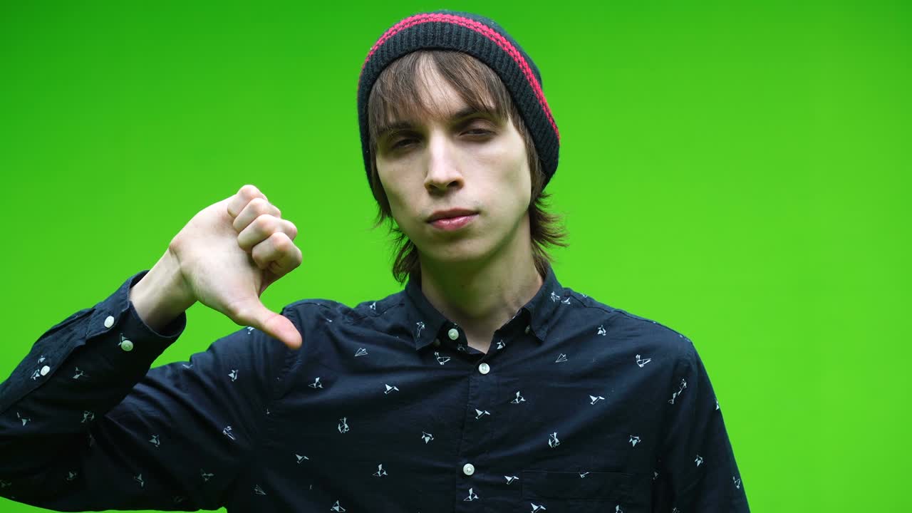 젊은이가 제거 가능한 크로마 키 배경에 나쁜 기호를 하고 있습니다.