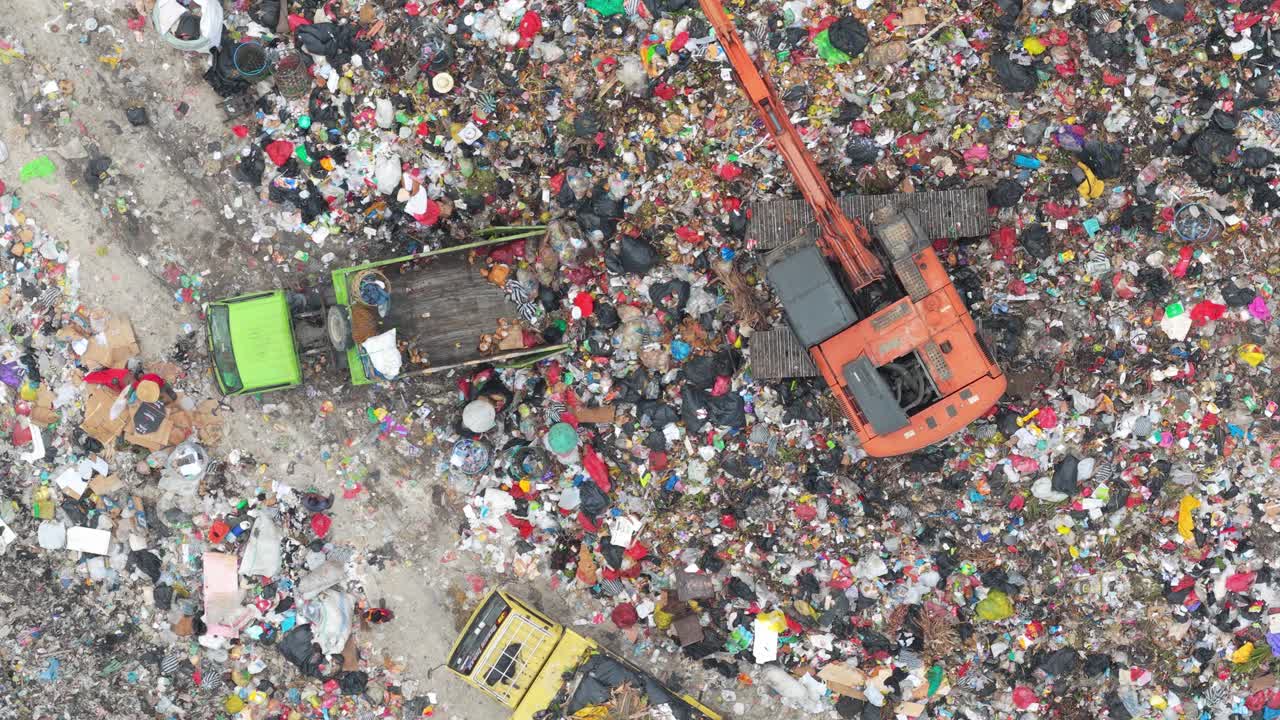 Escavatore che carica rifiuti su un camion in una discarica