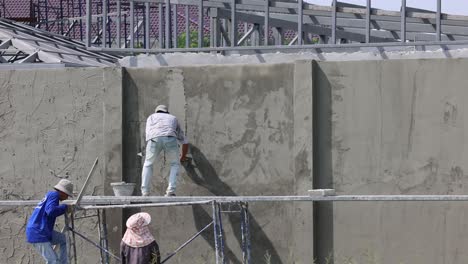 workers plastering a concrete wall together