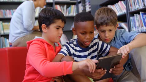 Front-view-of-mixed-race-schoolboys-studying-on-digital-tablet-in-the-school-library-4k