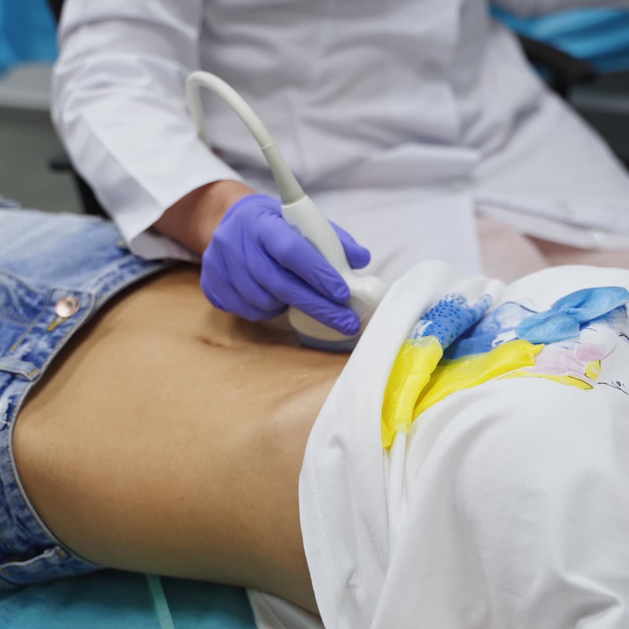 Unrecognized girl lies on the doctor's couch. Specialist performs ultrasound check of patient's abdomen