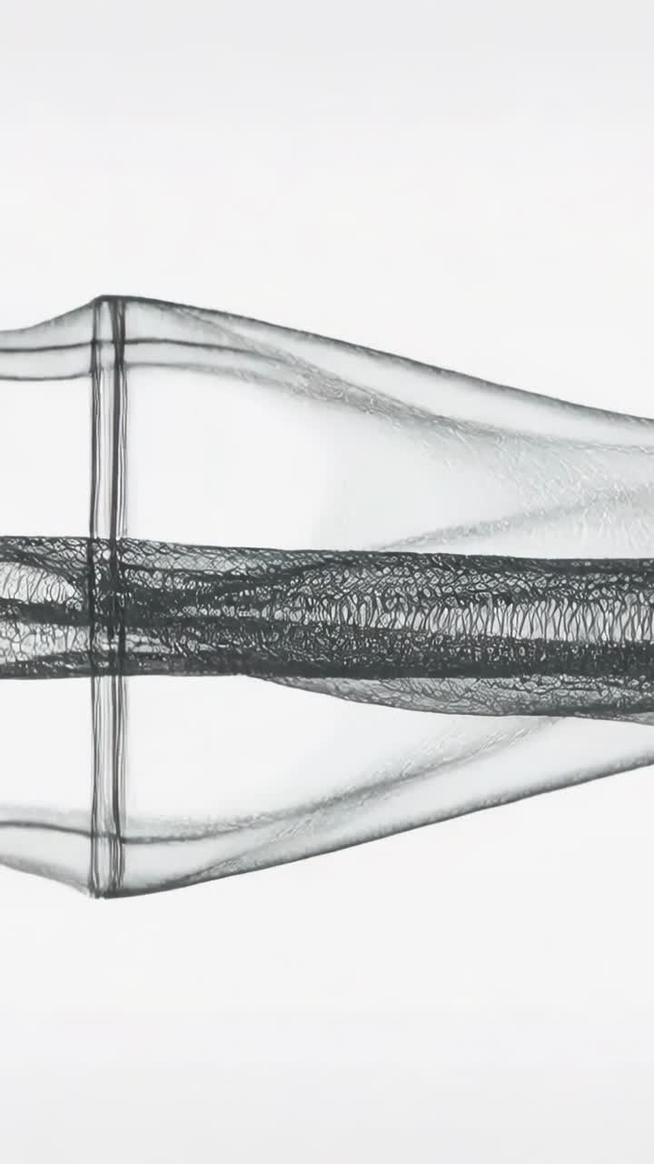 Vertical video: Frames shifting sheer mesh ribbons moving and morphing at studio showing knit core