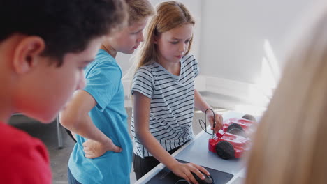 grupo de estudiantes en la clase de codificación de computadoras después de la escuela aprendiendo a programar un vehículo robot