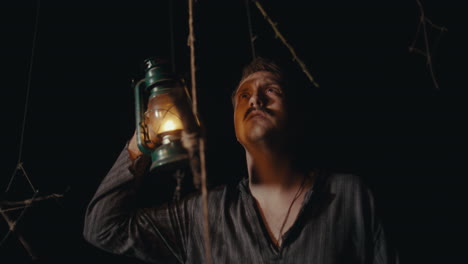 man with lantern in a dark, mysterious setting
