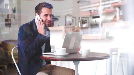 joven empresario en una mesa en un café hablando por teléfono