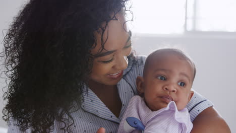 Liebevolle-Afroamerikanische-Mutter-Im-Schlafanzug,-Die-Ihre-Kleine-Tochter-Im-Schlafzimmer-Zu-Hause-Kuschelt