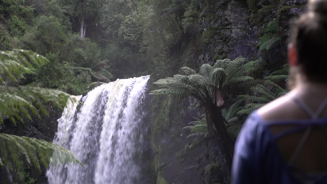 Close up of waterfall with girl out of focus admiring