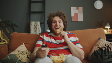man watching tv and eating chips