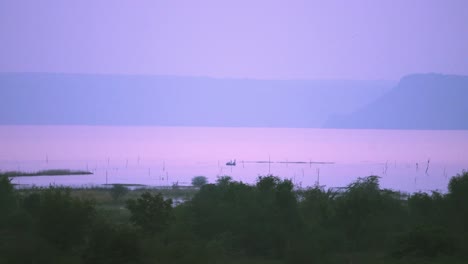 distant fisherman boats doing fishing during the time of dawn in tighra reservoir of gwalior