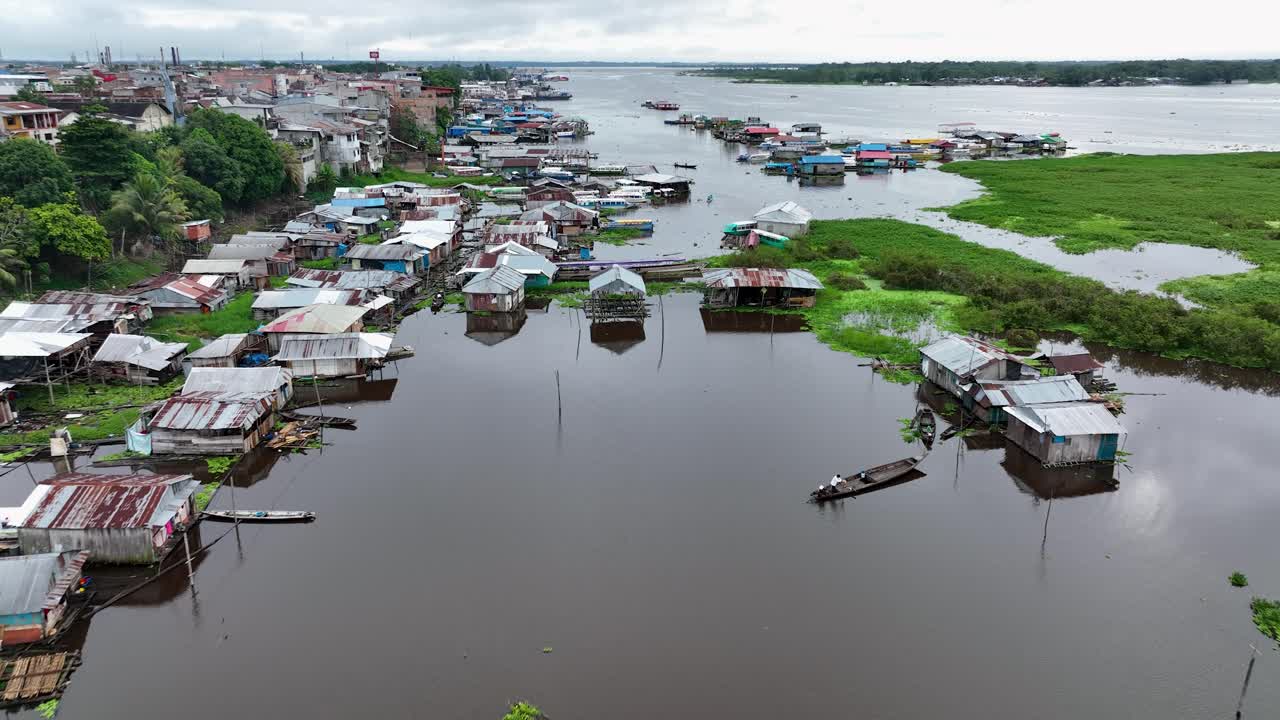 Aerial drone fly view of wooden floating houses and houses on stilts in small town on bank of the Amazon river close to Iquitos