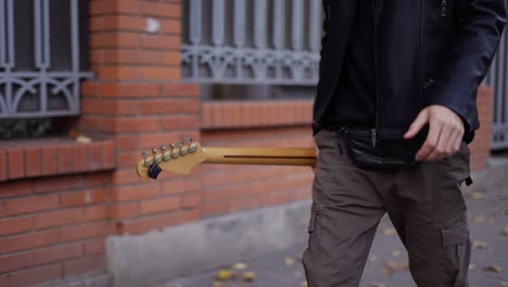 man walking down the street with a guitar