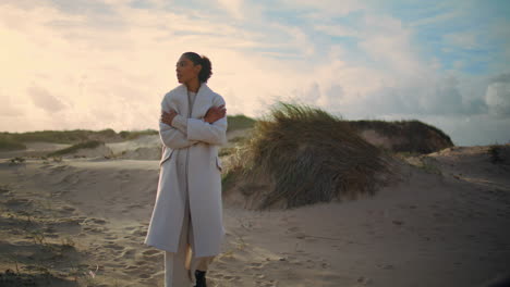 mujer solitaria admirando las dunas de la playa. modelo de cabello negro se enfría descansando en la orilla del mar