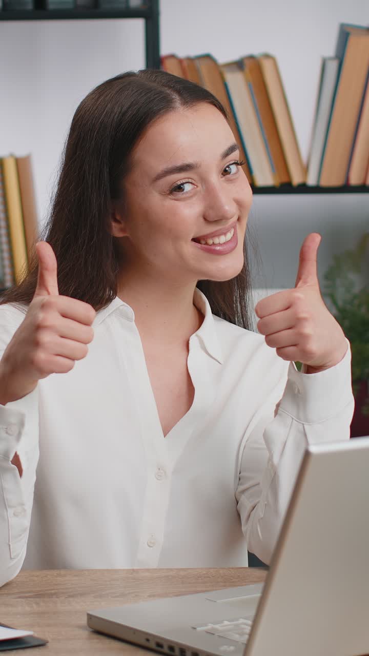 Una donna d'affari felice che guarda con approvazione la telecamera mostrando i pollici in alto come un segno positivo di buone notizie