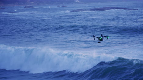 a drone flying across the ocean waves at sunset