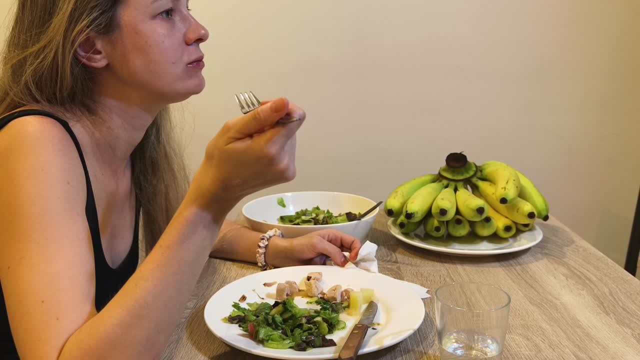 Woman eating salad and bananas