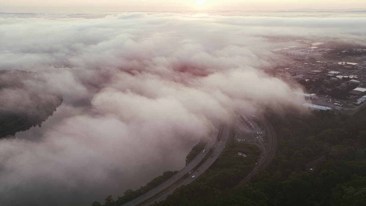 Drone footage shows a highway curving along the Tennessee River near Chattanooga, with fog drifting over the water and green forested banks