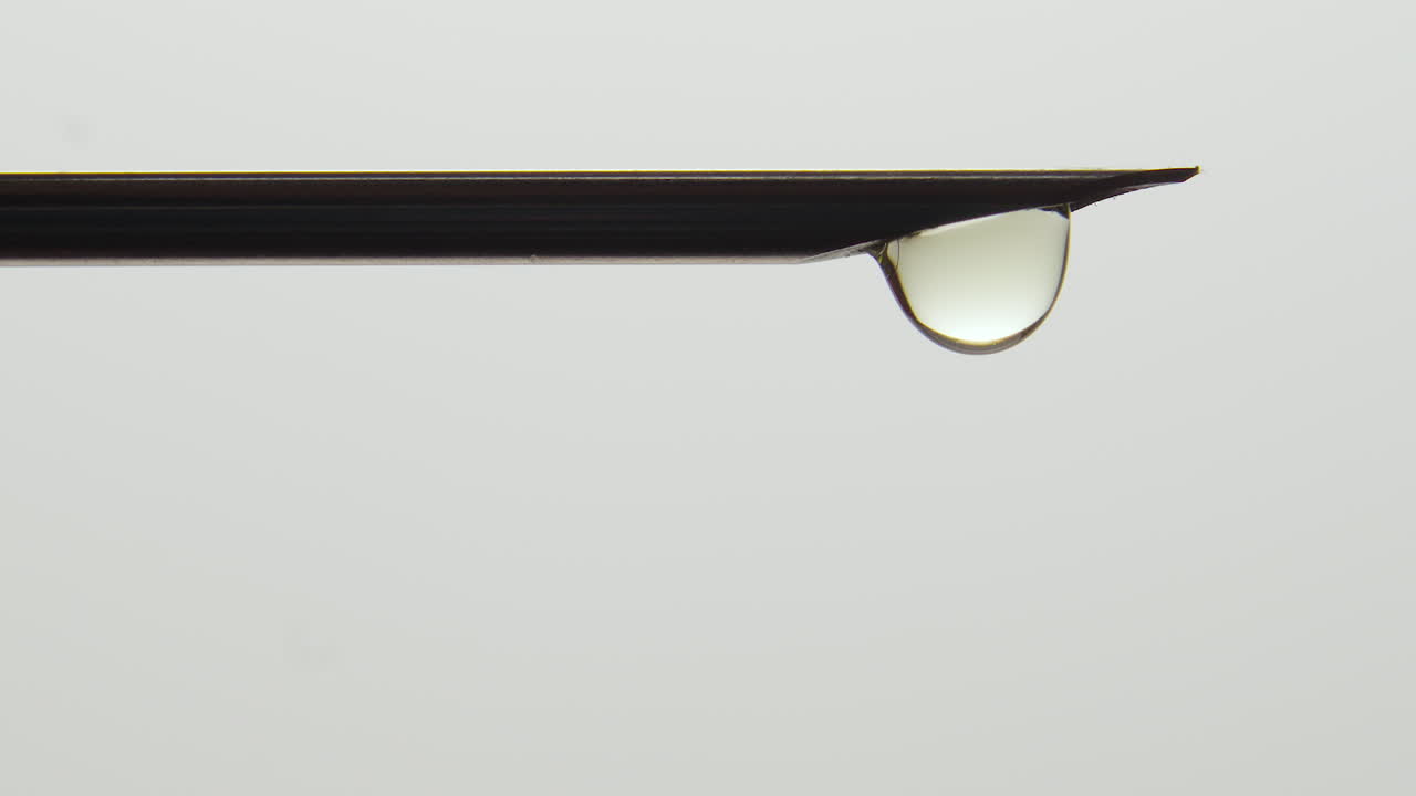 крупный план наконечника иглы, капающего в силуэте