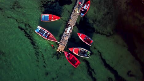 Overhead-dolly-in-view-of-a-wooden-walkway-with-fishing-boats-near-Kanoa-Beach,-Curacao,-Dutch-Caribbean-island