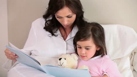 madre sonriente leyendo un libro en voz alta