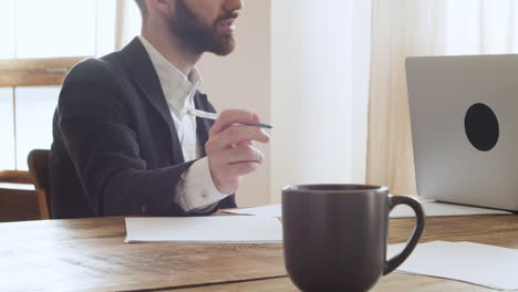 primer plano de un hombre de negocios sosteniendo un bolígrafo y debatiendo con su colega mientras se sienta a la mesa en la oficina