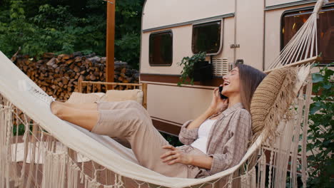 woman relaxing in a hammock by a campervan