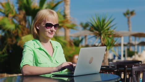 Frau-Tourist-Tippt-Auf-Einem-Laptop-Vor-Dem-Hintergrund-Mediterraner-Erholungsgebiete