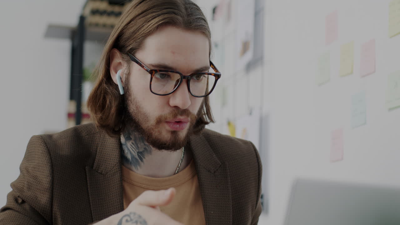 Man in office, working on laptop during video conference