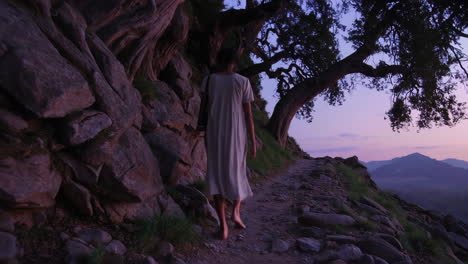 woman walking on a mountain path at sunset