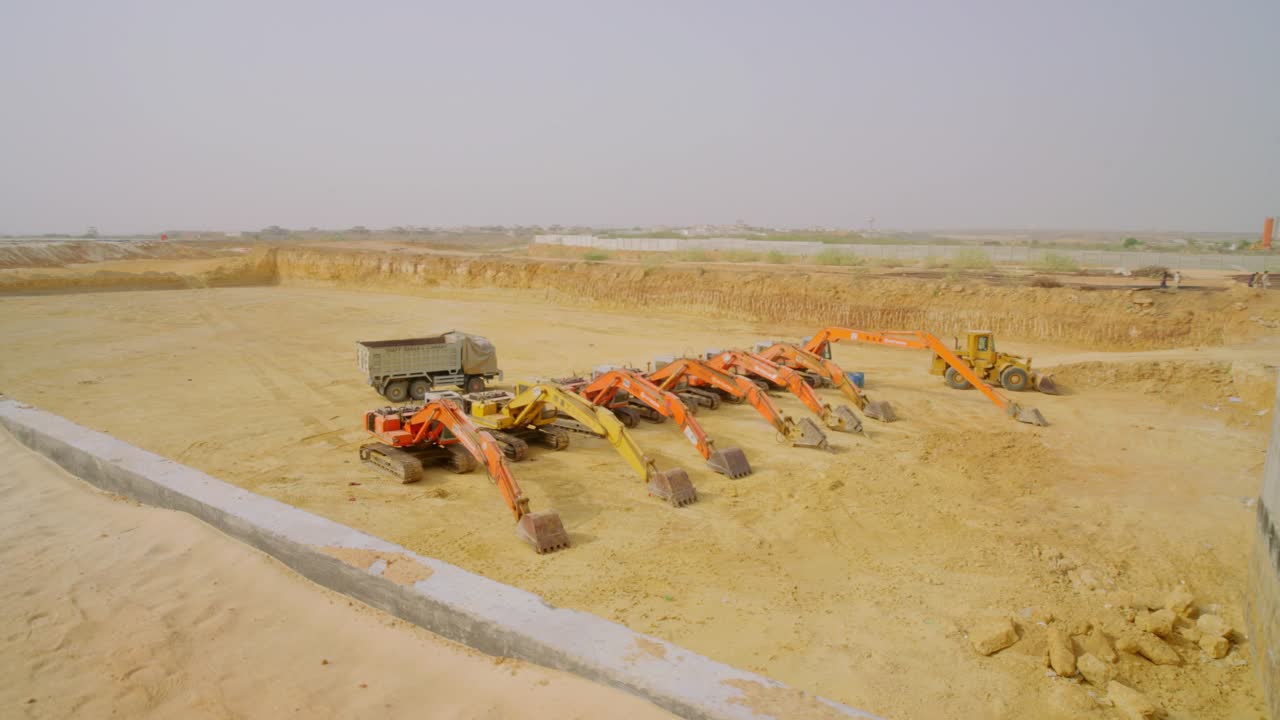 Construction site featuring excavators and heavy machinery on sandy terrain