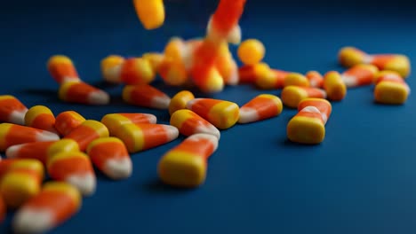 a colorful collection of candy corn spreading across a blue background, highlighting the sweet treats' unique shape and vibrant colors perfect for seasonal celebrations