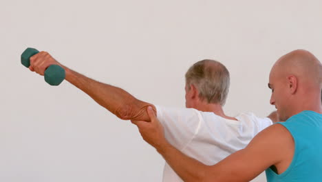 anciano y entrenador haciendo ejercicios con pesas