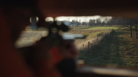 hunting rifle aims out of deer blind during deer hunting season