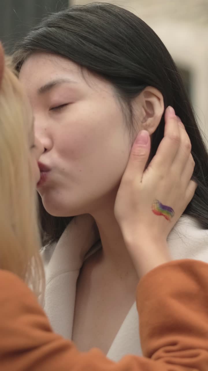 Lesbian couple kissing with pride flag tattoo