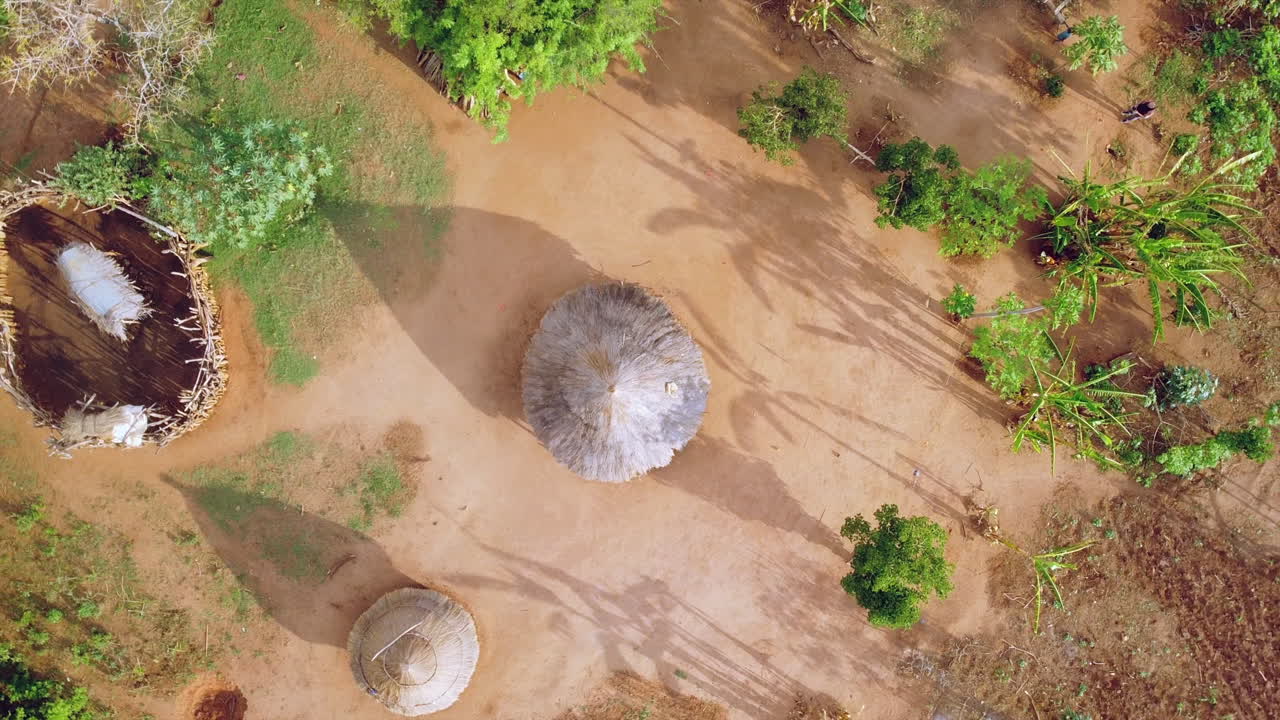 Droneoptagelse fra fugleperspektiv, der svæver op fra en stråhytte i Omodalens stammeområde.