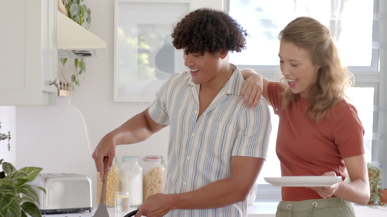 Young diverse couple cooking breakfast together in kitchen, sharing joyful moments, at home