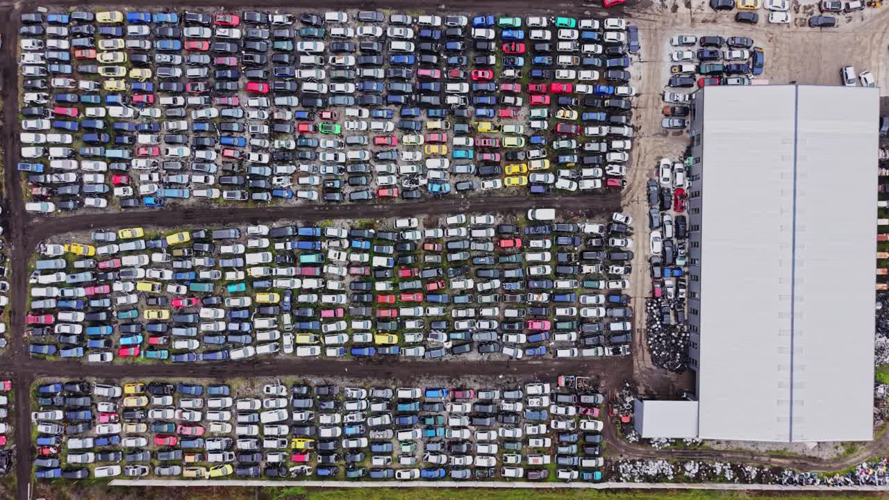 Autodemolizione con file di veicoli e un grande magazzino nelle vicinanze
