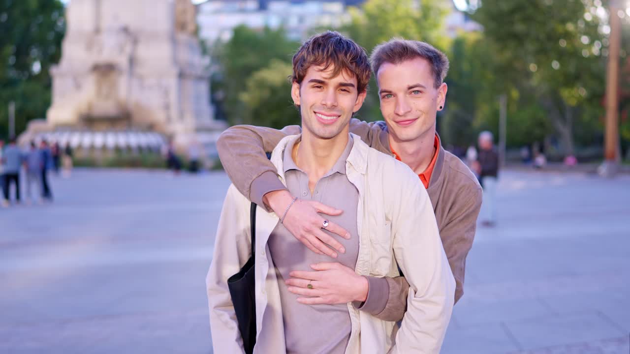 Coppia gay felice che si abbraccia e sorride in un parco cittadino