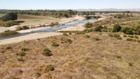 Aerial-fly-over-of-desert-land-and-plants-cut-through-by-a-rocky-creek