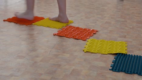 child walking on colorful reflexology mats