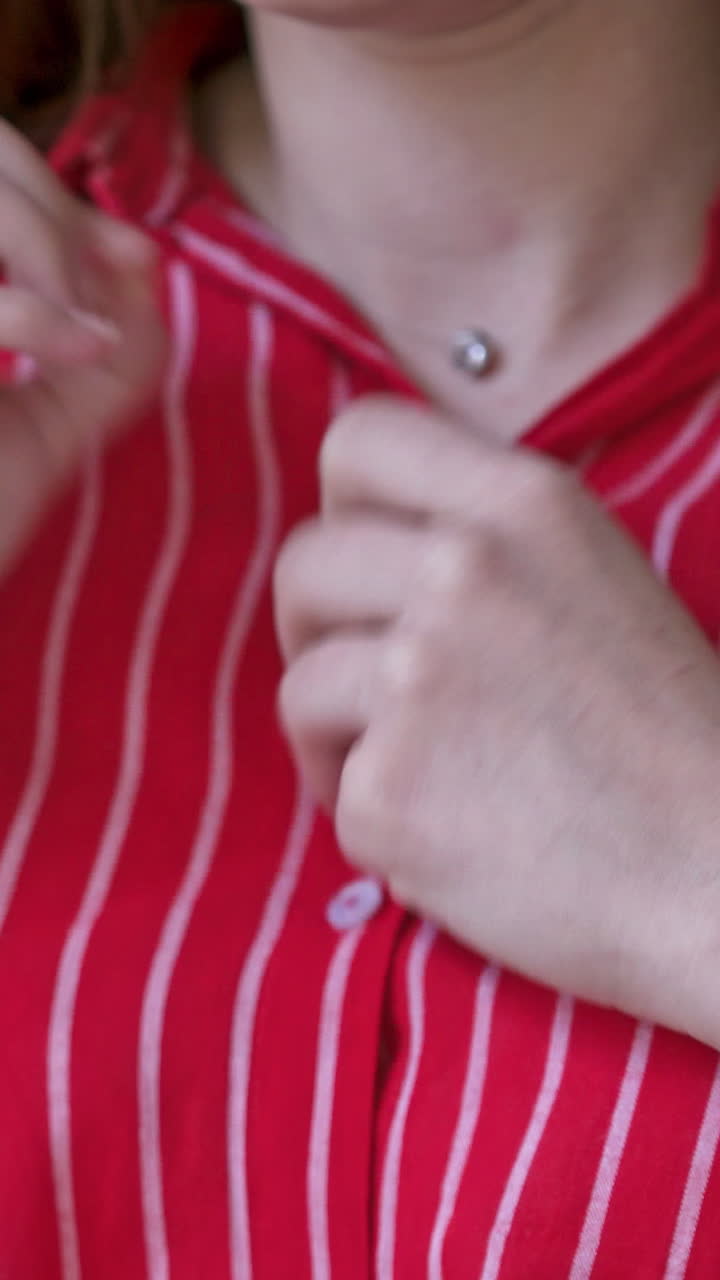 Woman hands close up buttons on shirt. Close up of hand woman adjusting shirt button. Vertical video
