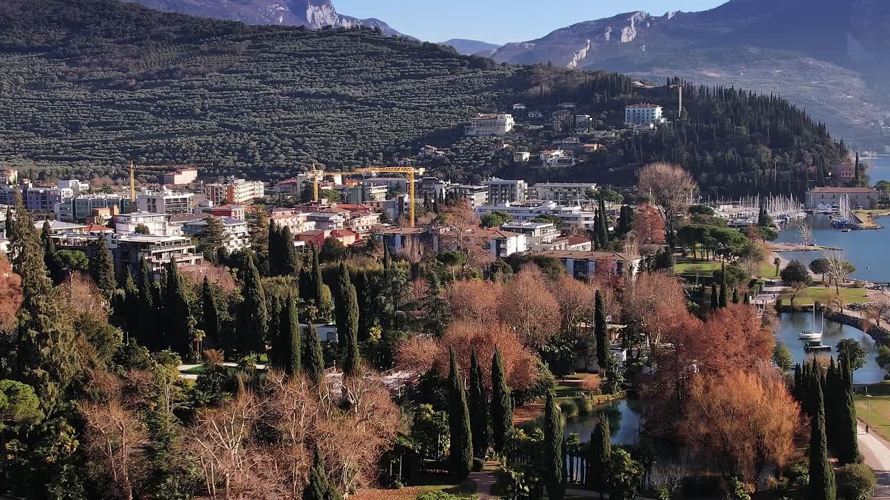 Güneşli bir günde İtalya Alpleri'ndeki gölün yakınında dağlar ve kasaba