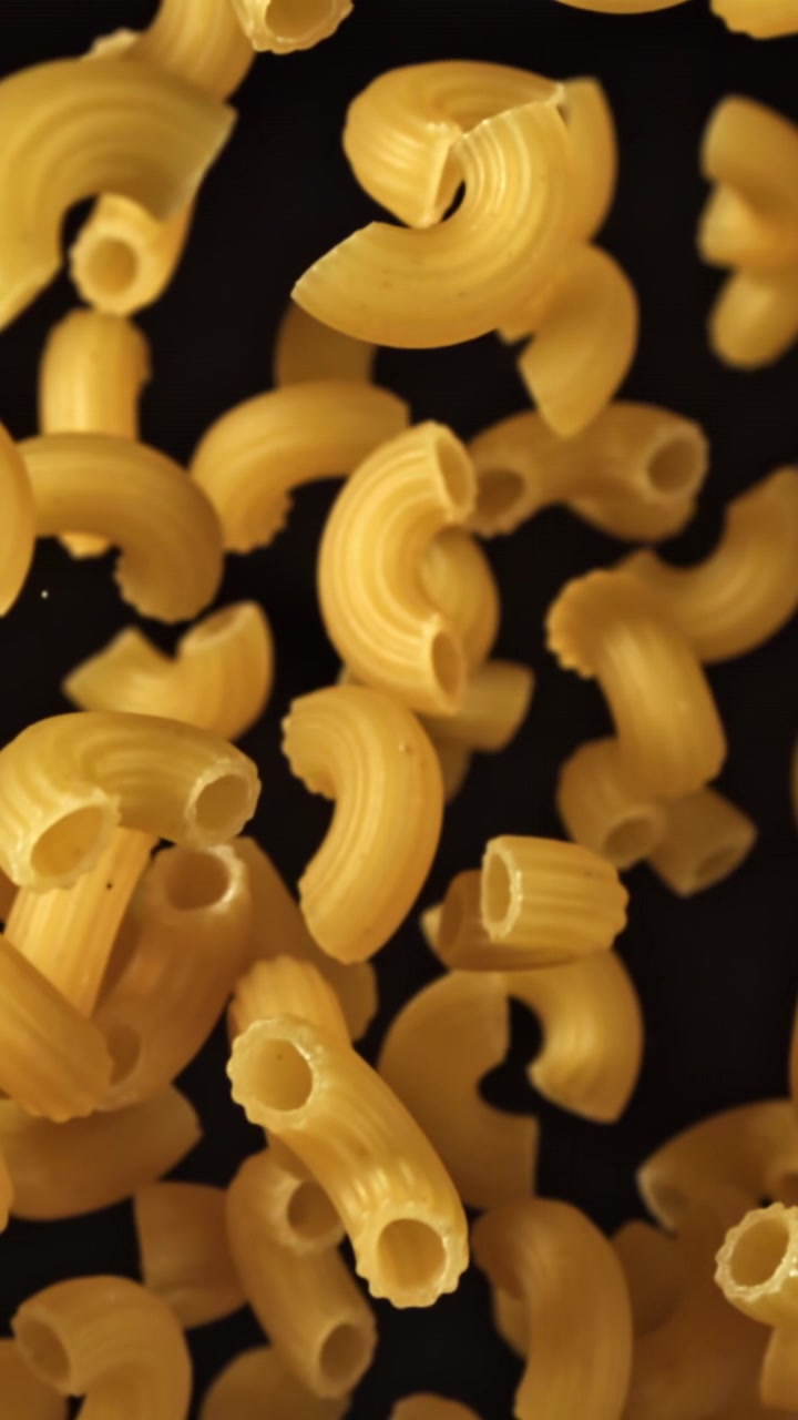 Pasta Maccheroni Cruda che Cade al Rallentatore su Sfondo Nero.