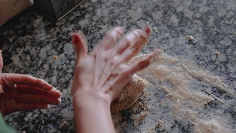 woman kneading whole wheat dough with circular movements on floured countertop