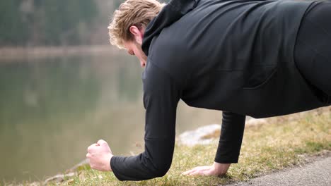 hier ist ein athletischer junger mann mit blonden haaren zu sehen, der eine mischung aus planken und liegestützen macht