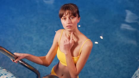 pretty young girl in a yellow swimsuit in the pool smiling