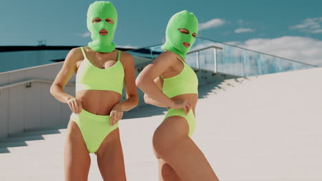 two women in lime green swimsuits and balaclavas