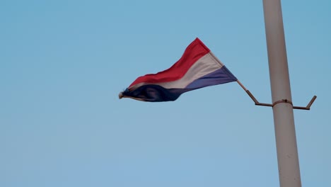 flag with red, white and blue colors on a pole waving strongly in the wind