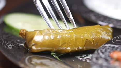 close-up of dolma (stuffed grape leaf) on a plate with a fork