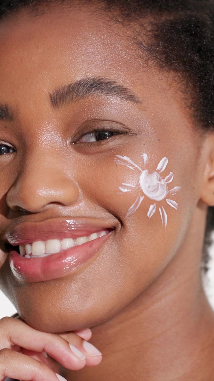 Young Woman With Sunscreen Drawn on Cheek Smiling at Camera