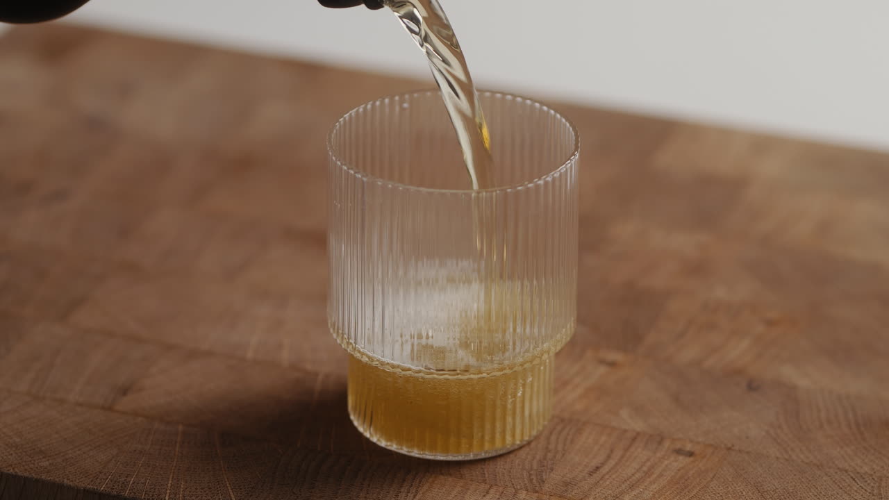 Versare birra dalla bottiglia in un bicchiere a casa in cucina.